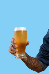 beer glass, male hand holds a glass with cold beer, foam on top of beer glass. on blue background