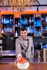 Young bartender preparing an orange cocktail. Concept: drinks, nightlife, fun