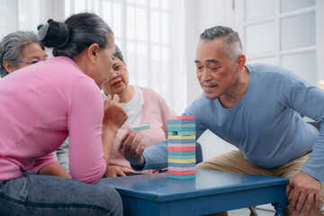 Obraz premium Senior playing a wood block on the tower. People pulling wood block on the tower. Senior lifestyle at home. Risk to make growth concept.
