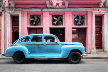 Pale blue car park in front of a pink wall with 3 ventilation fans in Havana - Cuba