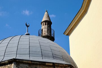 Fototapeta na wymiar stone Turkish minaret and mosque in Pecs, Hungary. diminishing perspective. low angle view. Islamic architecture. landmark building. named after Jakovari Hassan. blue sky. travel and architecture.