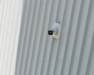 Close-up photo of a security camera mounted on a tin wall	of a modern building