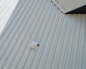 Close-up photo of a security camera mounted on a tin wall	of a modern building