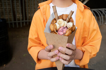 Hong Kong or bubble waffle with ice cream and chocolate tubes in the hands of a child