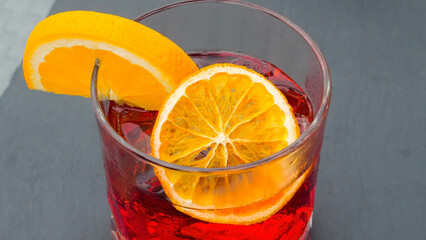 Close-up of beautifully decorated alcohol cocktail with orange slices in a glass at an outdoor restaurant. Luxurious drink exudes freshness and is perfect for a summer beach vacation.