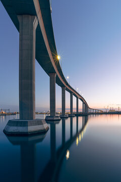 The Jordan Bridge over the Elizabeth River on the border of Norfolk and Chesapeake Virginia against a beautiful red, purple, pink, and blue sunset	
