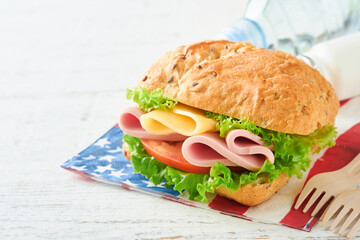 4th of July American Independence Day traditional picnic food. American sandwich or Burger on white, American flags and symbols of USA Patriotic picnic holiday on white wooden background. Top view