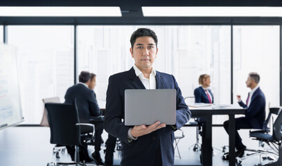 confidence asian business man hold laptop to present on board meeting date with business partner in the high building meeting room.