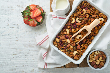 Homemade granola with greek yogurt or milk and cashews, almonds, pumpkin with dried cranberry seeds in old bowl on white rustic wooden table background. Healthy energy breakfast or snack. Top view.