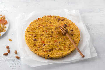 Baked vegan millet flatbread with dried fruits and nuts, sprinkled with honey on a light blue background