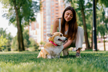 a young girl a zoopsychologist calms down a corgi dog in the park the dog sits next to the owner who praises her