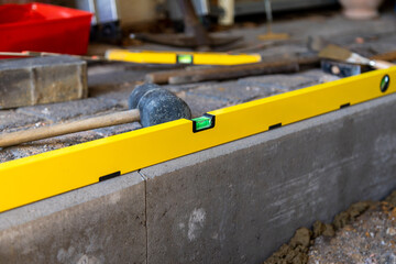 Wasserwage liegt bei Bauarbeiten auf einer Baustelle gerade auf einem Stein