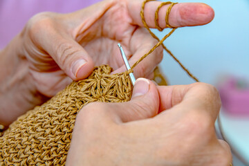 Close-up of young woman hands, knitting a bag