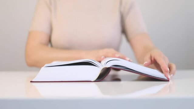 A woman is reading a book in a bright room.
