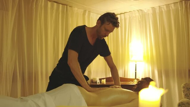 Massage session - master massaging the bare back of his female client