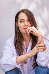 Portrait of young woman with beautiful blue eyes and brunette hair posing at sunlight