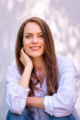 Fototapeta premium Portrait of young woman with beautiful blue eyes and brunette hair posing at sunlight