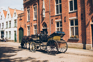 Fototapeta na wymiar row of old european dutch style houses in brown rust white cream colors with a horse drawn carriage on a street in belgium europe