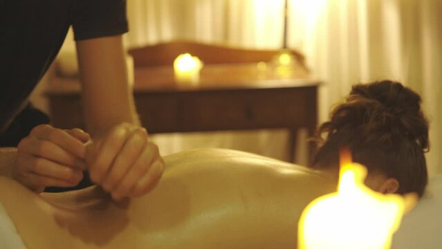 Massage session - master massaging the oiled bare back of his female client with his forearms