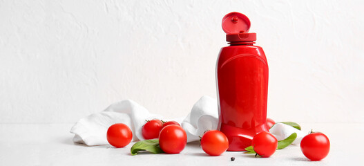Bottle of ketchup and tomatoes on white background with space for text