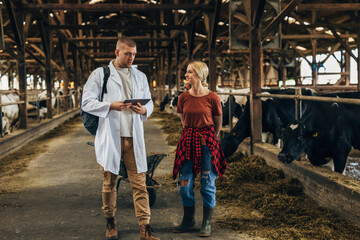 A woman farmer and a vet talk about health of cattle in a farm.