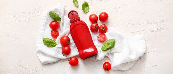 Bottle of ketchup and tomatoes on light background, top view