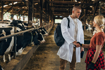 Handshake between a veterinarian and a cowgirl in a barn.