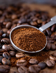 Roasted coffee beans and a metal spoon with ground coffee