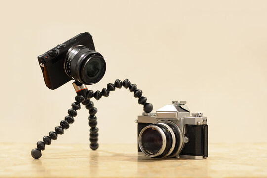 A photo of a small and modern camera looking and trying to take photo with an old film camera 