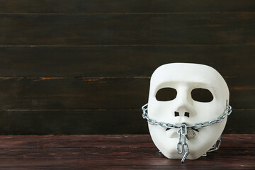 Mask with chain and lock on dark wooden background. Censorship concept