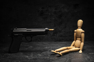 Wooden mannequin and gun loaded with cigarette on dark background. Stop smoking concept