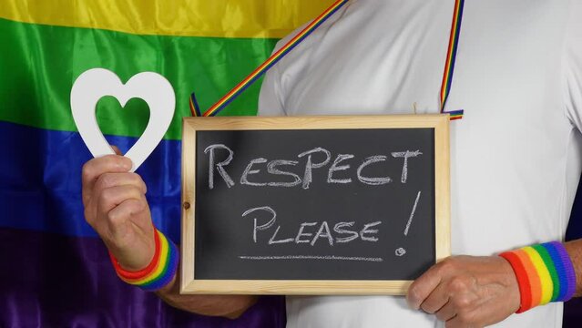 Gay boy and LGBT sympathizer proudly claims homosexual rights by holding up protest signs and with the rainbow flag in the background