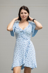 Portrait of a young beautiful dark-haired girl in a summer dress on a gray background.