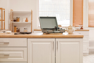 Record player with vinyl disk, cups and teapot on counter in kitchen