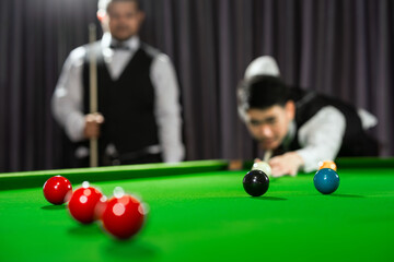 Asian man playing snooker, snooker club, Asian man playing snooker with selective focus on snooker ball and snooker ball movement.