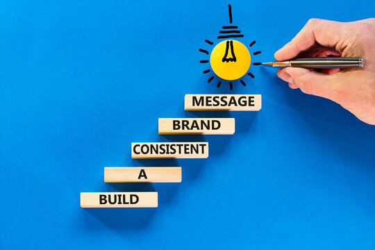 Consistent brand message symbol. Concept words build a consistent brand message on wooden blocks. Businessman hand. Beautiful blue background. Business consistent brand message concept. Copy space.