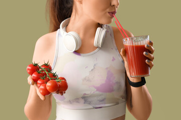 Sporty young woman with tomatoes drinking vegetable juice on green background, closeup