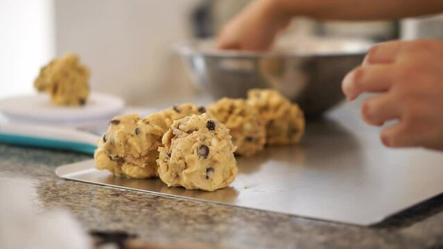 Horizontal video of the hands of an unrecognizable person preparing cookies in a kitchen.