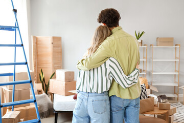 Young couple hugging in bedroom on moving day, back view