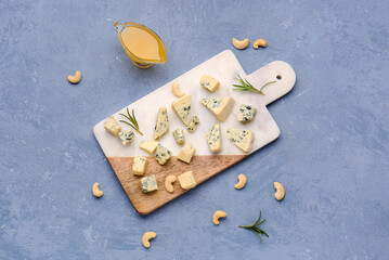 Board with pieces of tasty cheese and honey on grey background