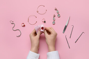 Woman cleaning beautiful jewelry on pink background