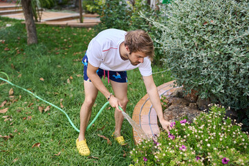 Chico joven regando las plantas en el jardin