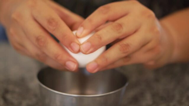 Stock video of a mundane movement, a person breaking an egg in a bowl.