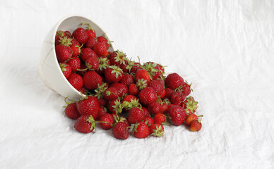 verturned cup with red strawberries on a white background.
