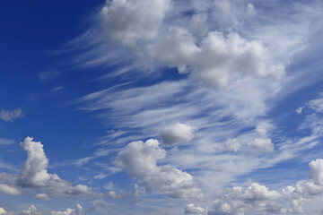 Fototapeta premium An image of a summer blue sky with a beautiful pattern of white clouds of various shapes.