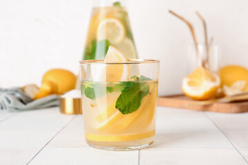Fototapeta premium Jug and glass with fresh lemonade on white tile table