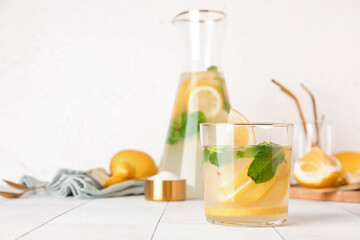 Jug and glass with fresh lemonade on white tile table