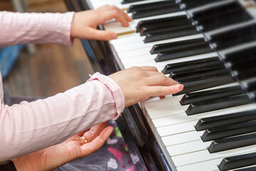 The child learns to play the piano under the guidance of a teacher.