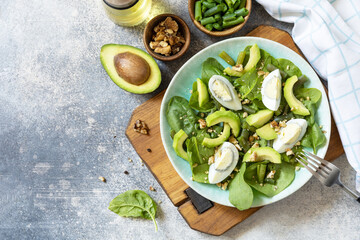 Organic green avocado and spinach salad with eggs, green beans, nuts on a stone table. Healthy food, summer healthy eating. View from above. Copy space.