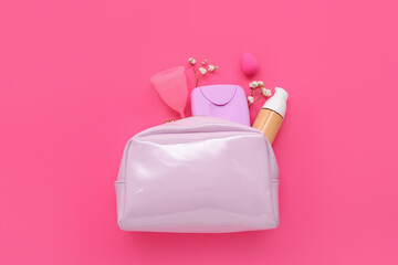 Lady's cosmetic bag with tampons storage box, foundation and menstrual cup on pink background